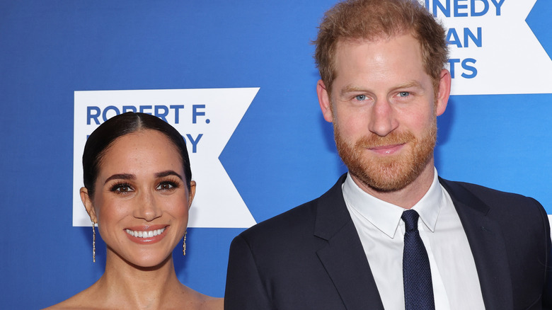 Prince Harry and Meghan Markle in front of blue background