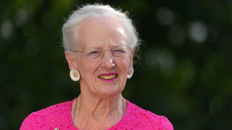 Queen Margrethe Denmark wearing daisy earrings and smiling to show bad teeth