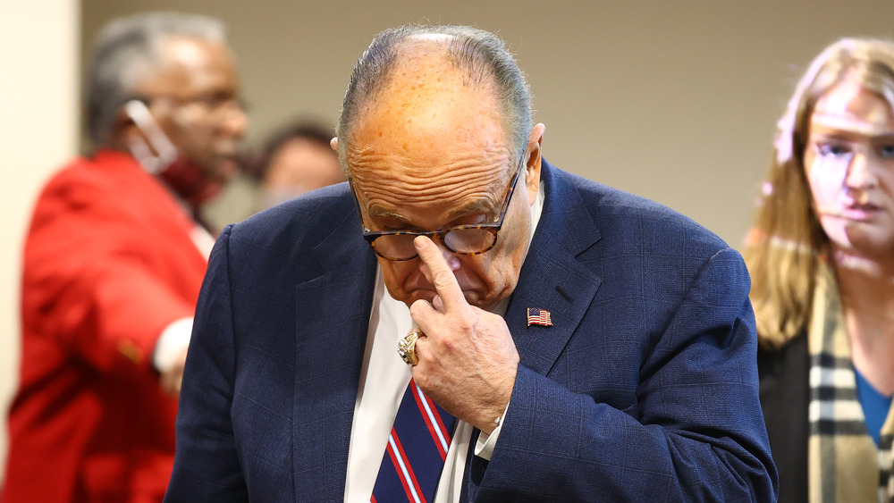 Rudy Giuliani adjusts his glasses with finger