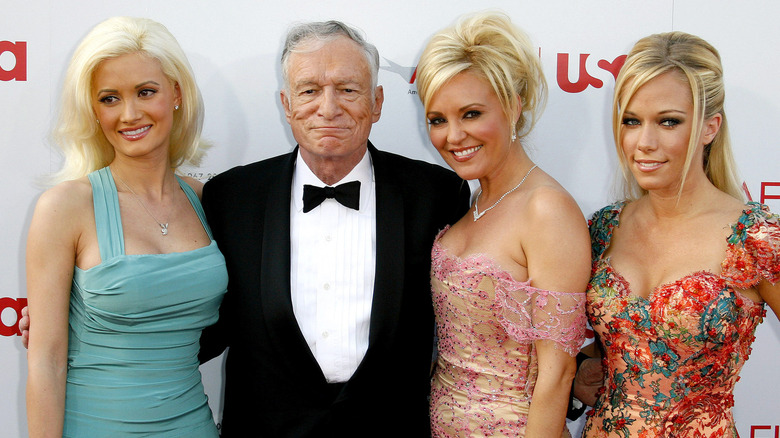 Holly Madison smiling with Hugh Hefner and other girlfriends