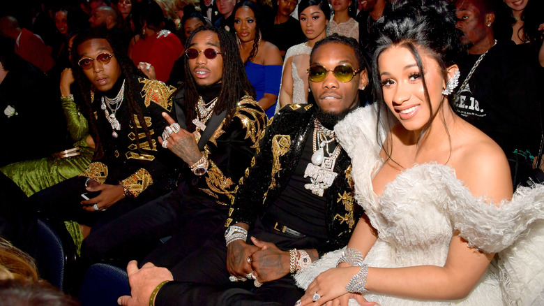 Cardi B seated next to Migos