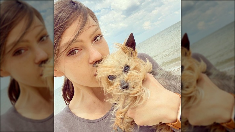 Aimeé Teegarden kissing her dog Gizmo on the forehead at the beach.