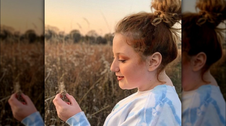 Bailee Ann smiling and looking down at a flower