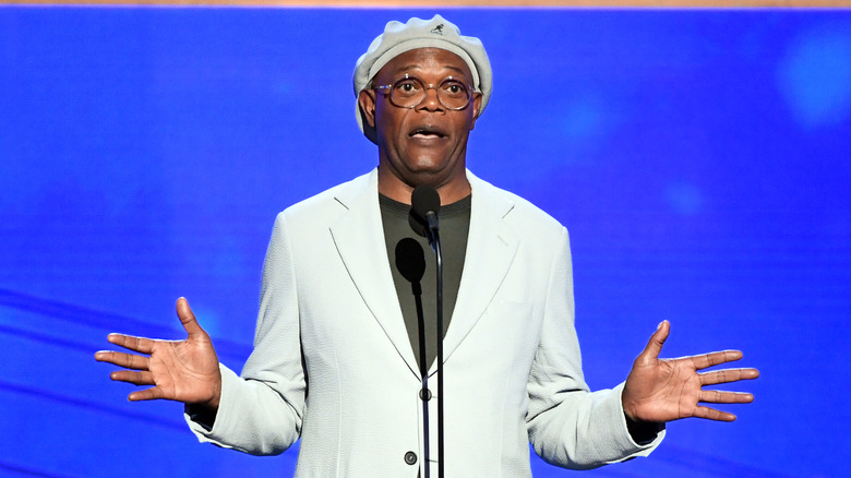 Samuel L. Jackson speaks in front of a crowd wearing a green shirt and a pale mint blazer