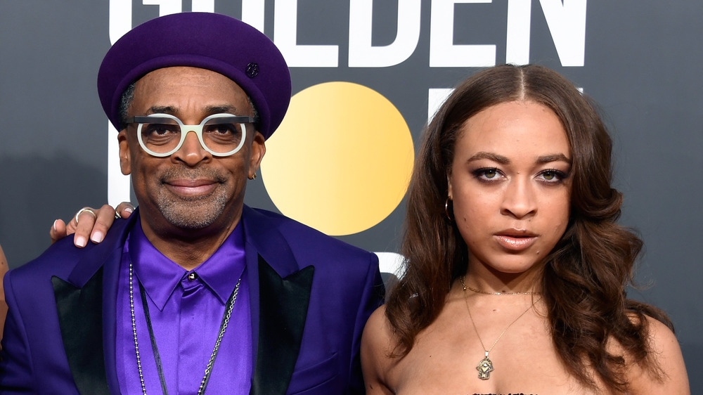 Spike Lee, smiling, wearing purple hat and suit, red carpet; Satchel Lee, not smiling, hair down, strapless dress, red carpet