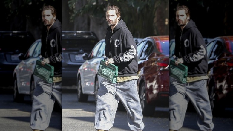 Scott Disick walking down street in hoodie and baggie jeans
