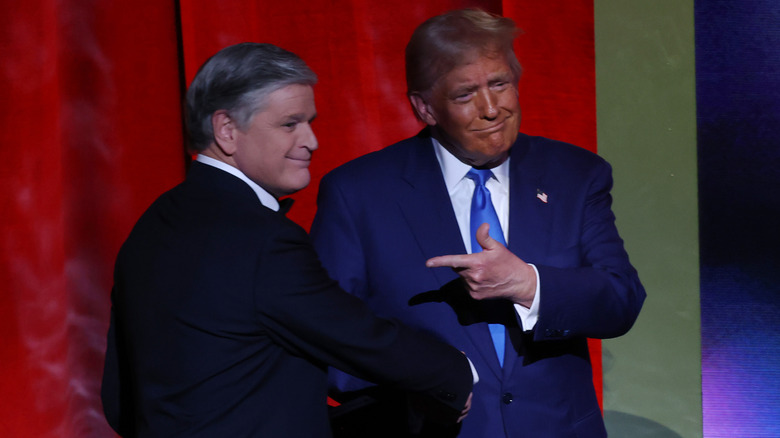 Donald Trump and Sean Hannity pose together on stage.