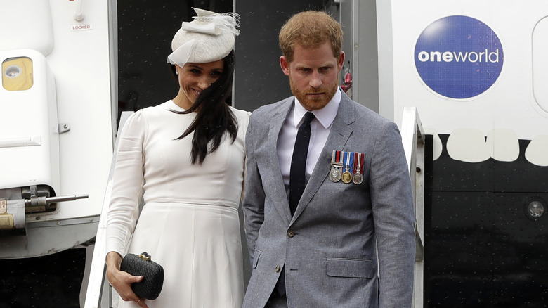 Meghan Markle and Prince Harry walking down the stairs of a plane