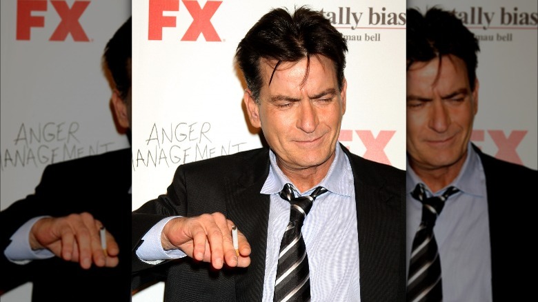 Charlie Sheen smokes on a red carpet