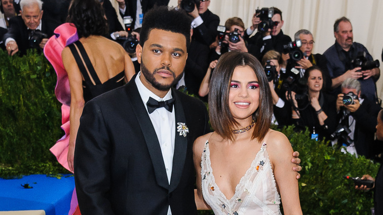 The Weeknd with arm around Selena Gomez