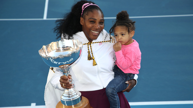 Serena Williams holding her daughter and a trophy