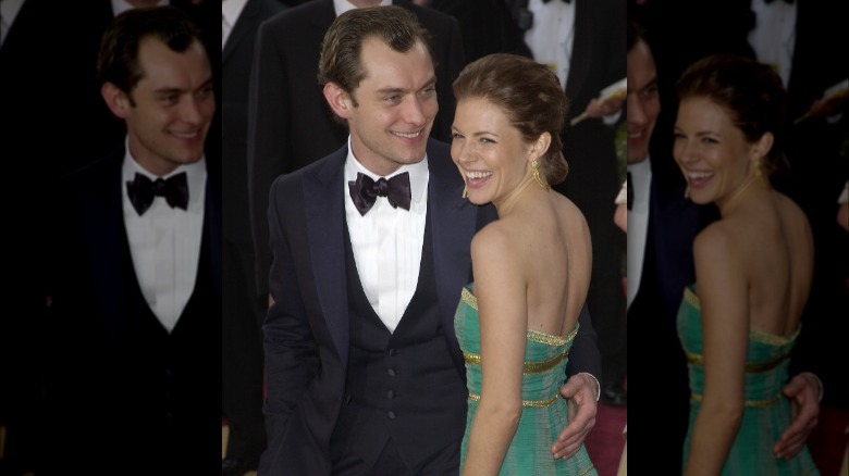 Jude Law and Sienna Miller laugh on a red carpet