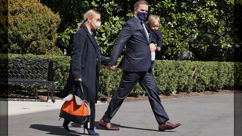 Hunter and Melissa Biden hold hands while he holds Beau