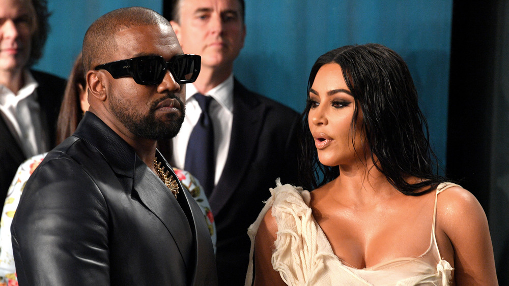 Kanye West in sunglasses with Kim Kardashian sporting wet-look hair 