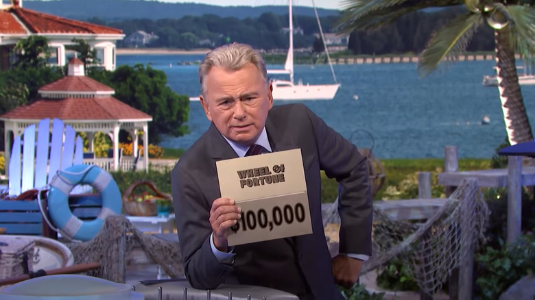 Pat Sajak holding $100,000 envelope