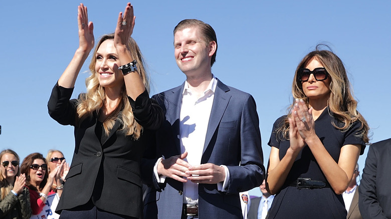 Lara and Melania Trump clapping, Eric Trump grinning