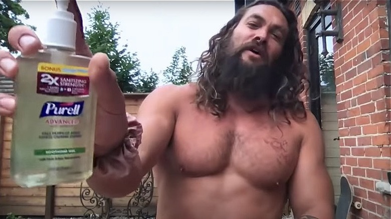 A shirtless Jason Momoa holds up Purell