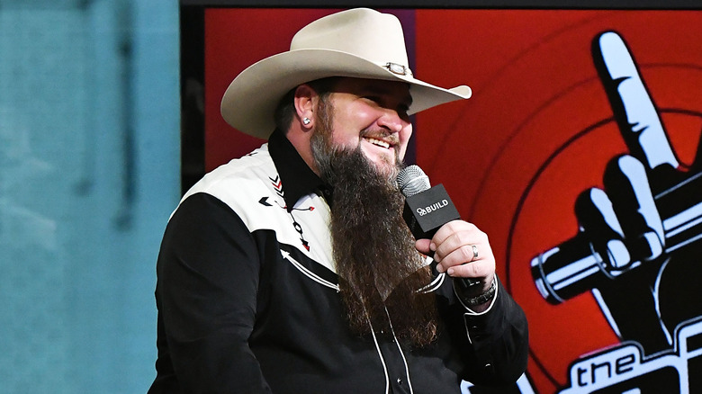 Sundance Head holding a microphone and smiling