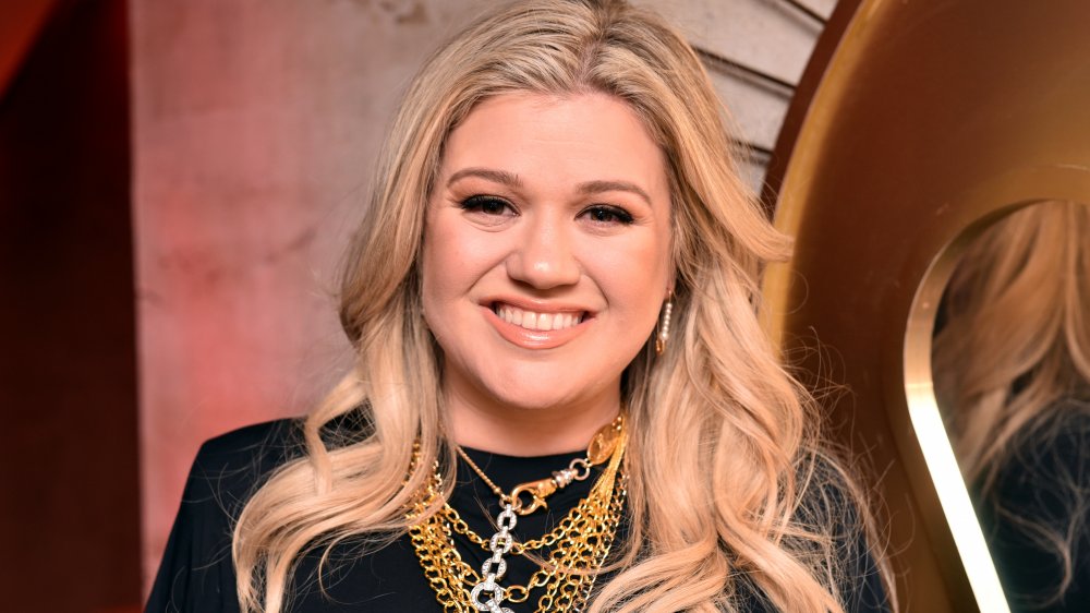 Kelly Clarkson in a black dress and gold jewelry, smiling