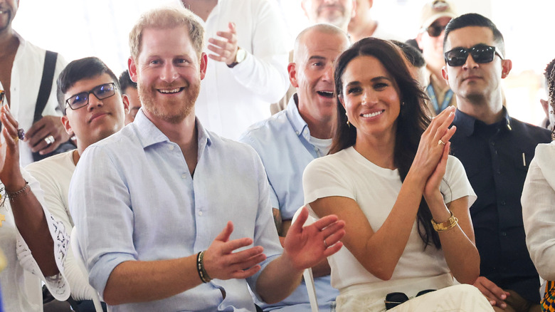 Prince Harry and Meghan Markle smiling and clapping