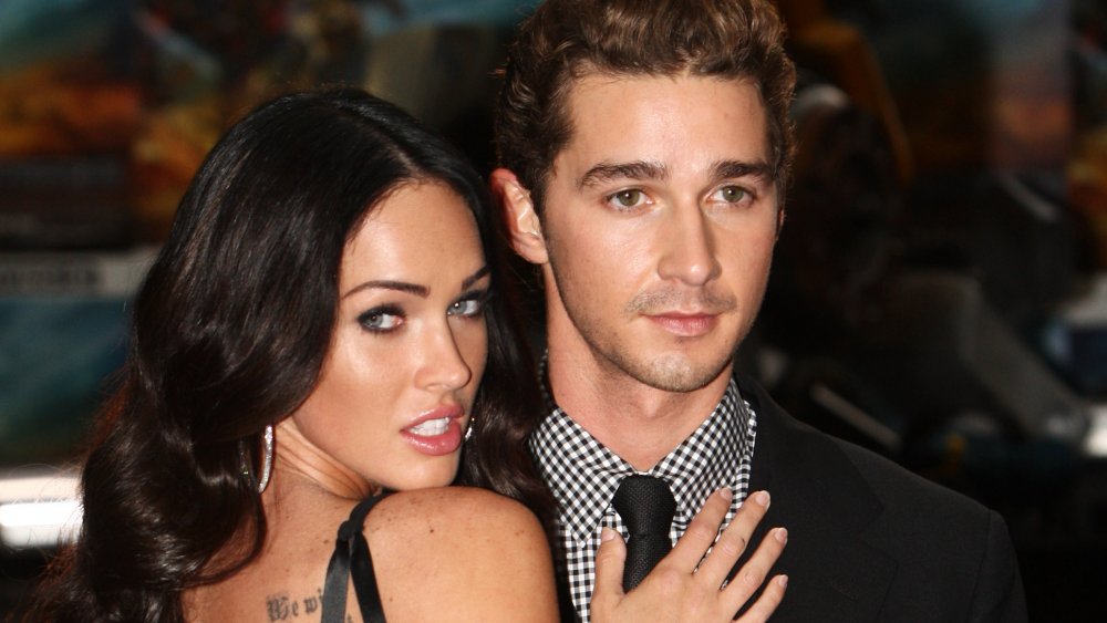 Megan Fox posing next to Shia LaBeouf with her hands on his chest at a Transformers premiere