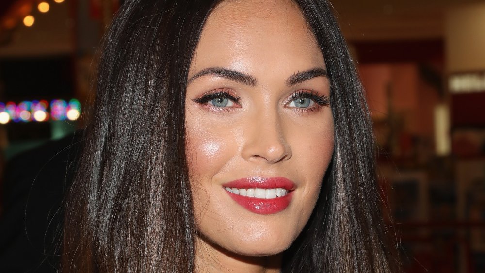 Megan Fox with straightened hair, smiling while looking off to the side