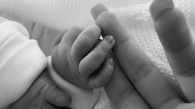 Sophia Grace's newborn baby's hand in hers