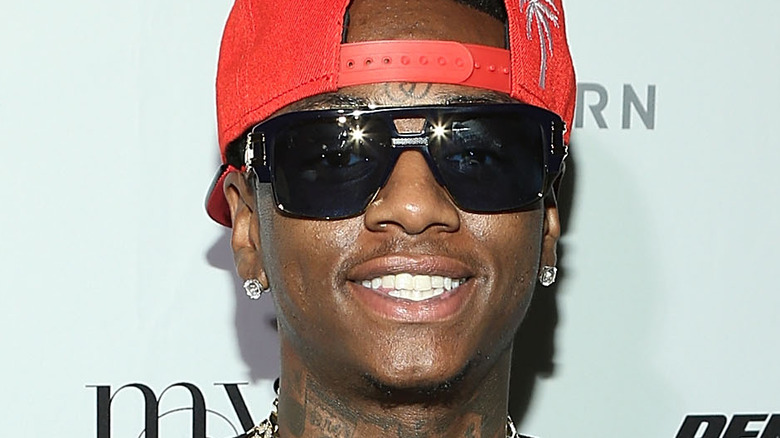 Soulja Boy wearing a red cap and dark glasses