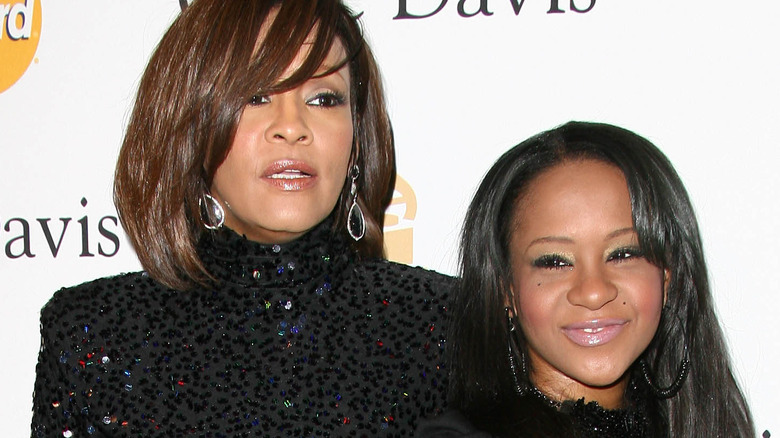 Bobbi Kristina Brown smiling beside Whitney Houston