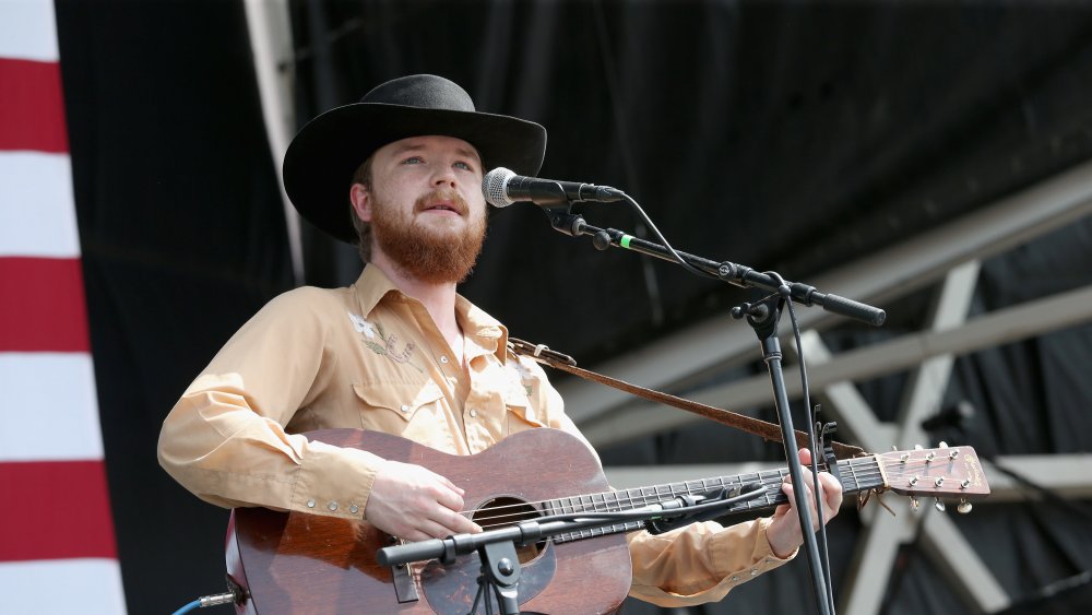 Colter Wall in cowboy hat and guitar on stage