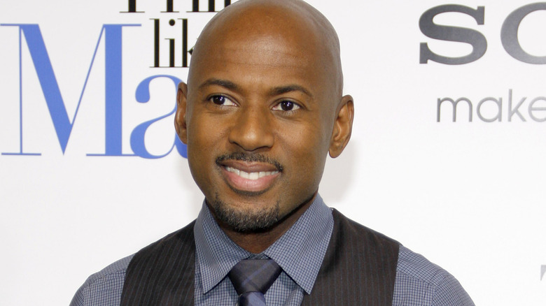 Romany Malco smiling in a vest and tie