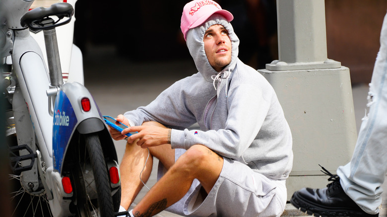 Justin Bieber sitting on the sidewalk