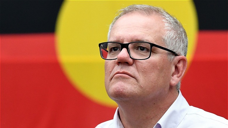 Scott Morrison in front of an aboriginal flag