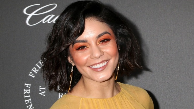 Vanessa Hudgens in a yellow top with gold hoop earrings