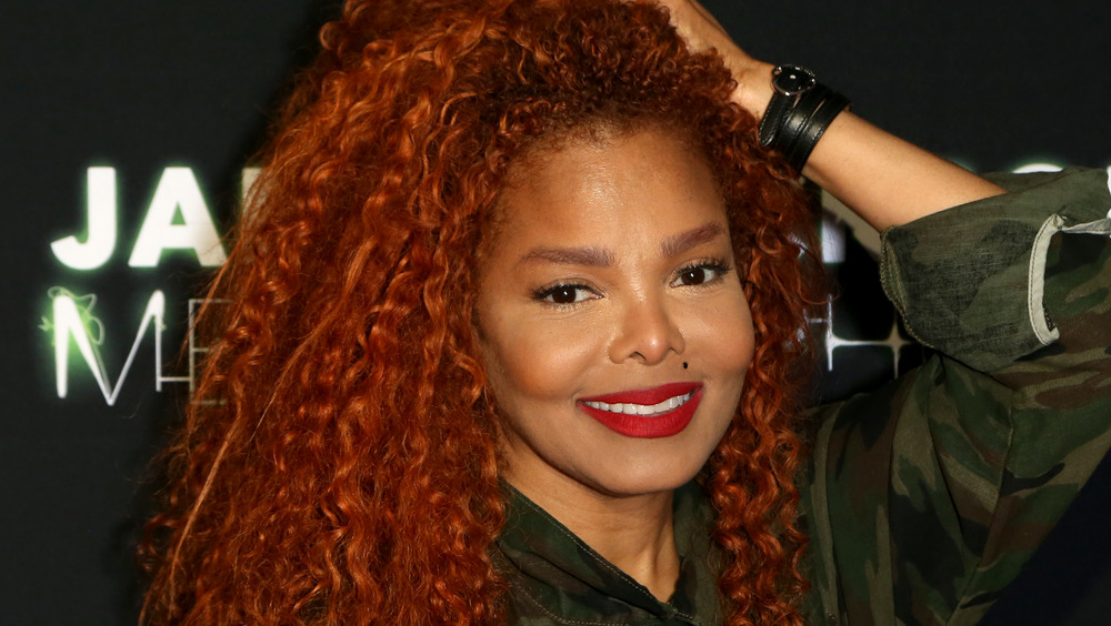 Janet Jackson red hair, hand on head