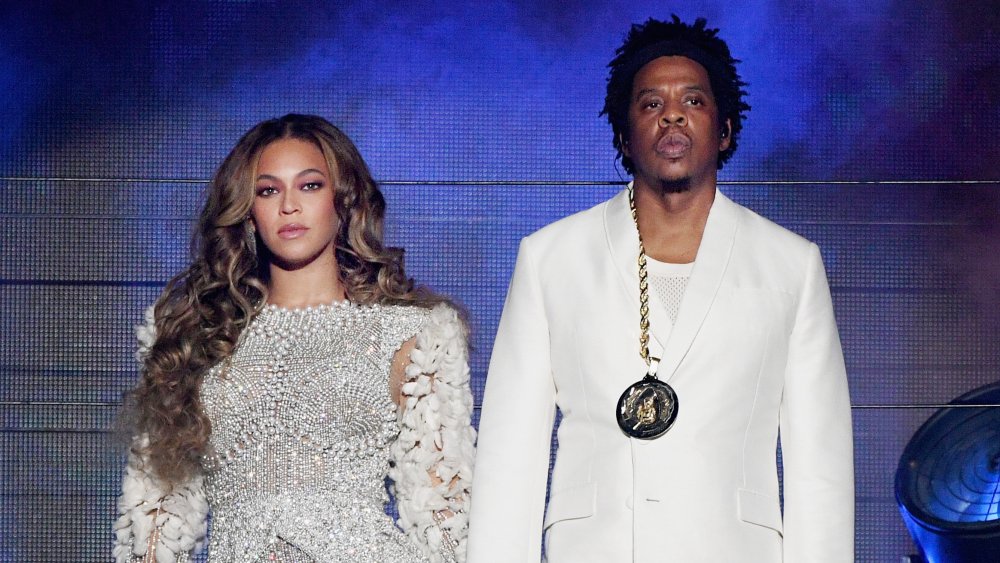 Beyonce and Jay-Z performing on stage together, both looking serious and looking out into the crowd