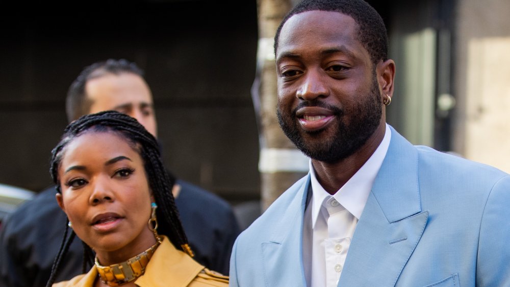 Gabrielle Union in a yellow trench coat, Dwyane Wade in a light blue suit