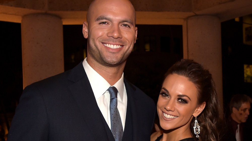 Mike Caussin in a blue blazer, Jana Kramer in a black dress, both smiling and holding each other