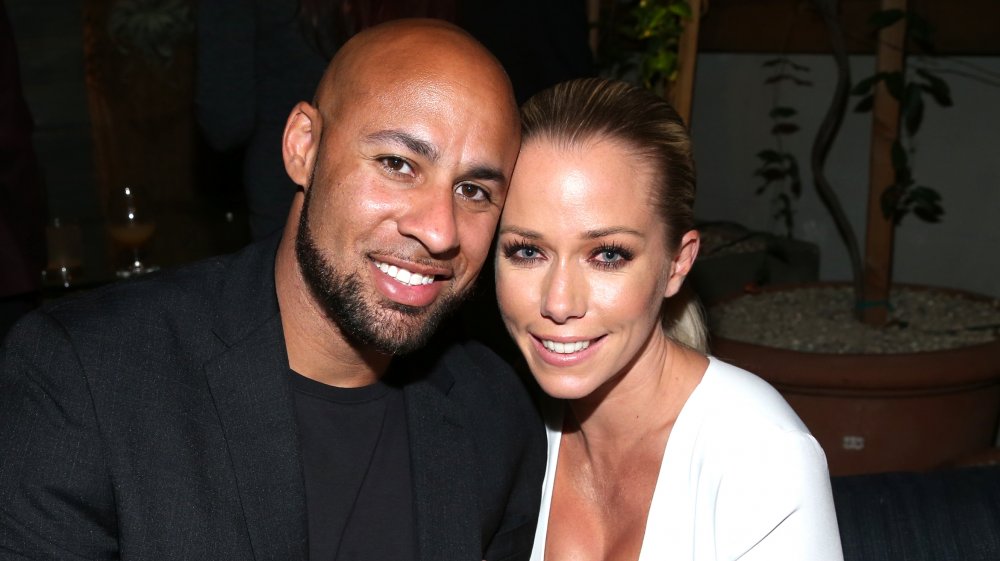 Hank Baskett in black, Kendra Wilkinson in white, both smiling while posing together