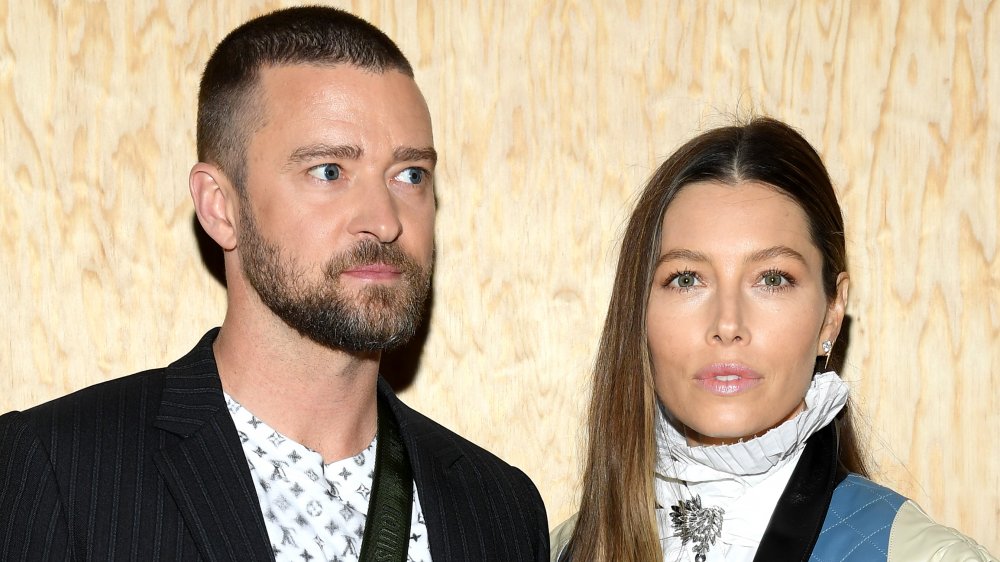 Justin Timberlake in a black-striped blazer and patterned white t-shirt, Jessica Biel in a white-and-blue outfit