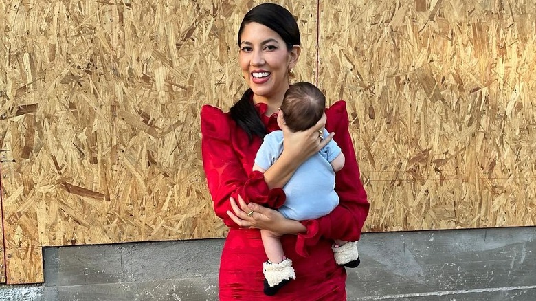 Stephanie Beatriz smiling while holding her baby