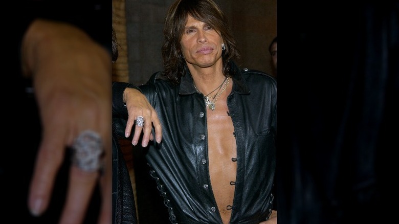 Steven Tyler looking tanner in an open leather shirt and pink lipstick