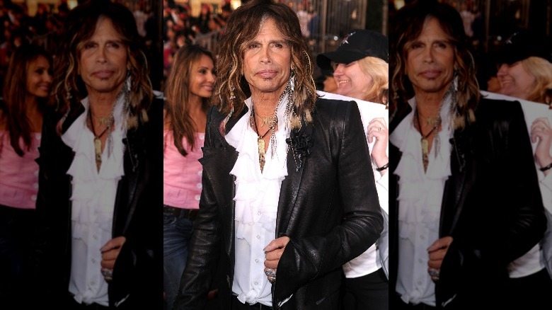 Steven Tyler posing in a leather blazer and white frilly shirt