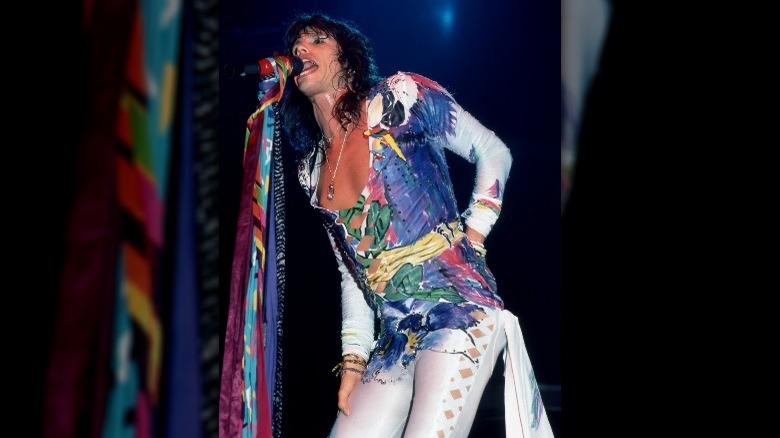 Steven Tyler performing in a multicolored jumpsuit 80s