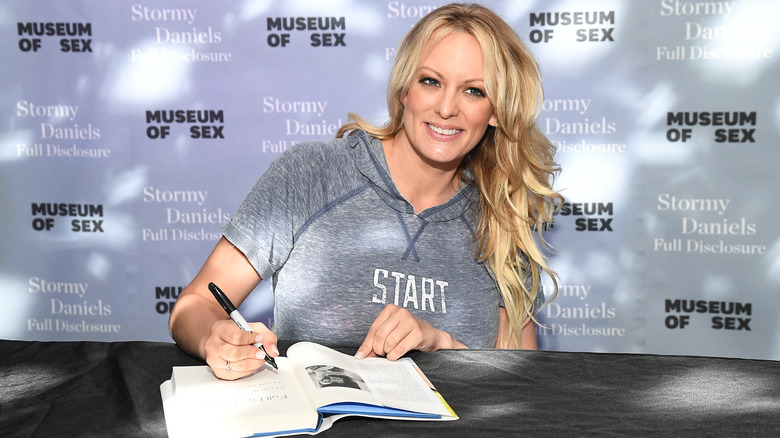 Stormy Daniels smiling and signing book