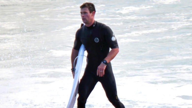 Chris Hemsworth with surfboard, walking