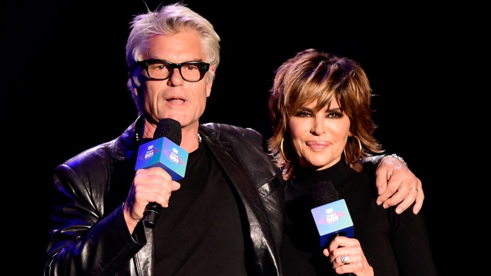 Harry Hamlin, Lisa Rinna in matching black, speaking onstage at the 2016 iHeart80s Party