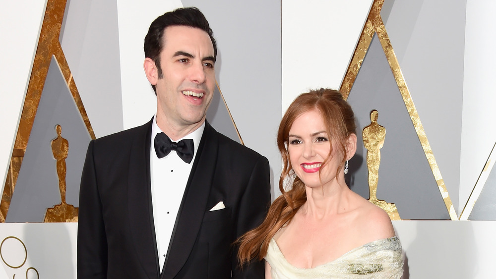 Sacha Baron Cohen and Isla Fisher smiling and posing on the Oscars red carpet 