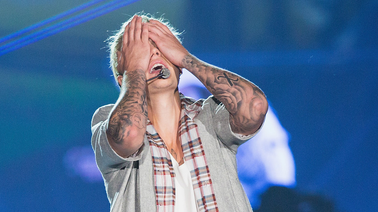 Justin Bieber with hands over face on stage