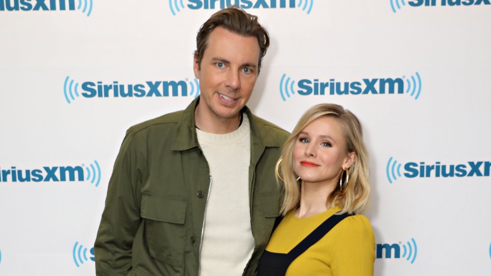 Dax Shepard and Kristen Bell in front of SiriusXM promo wall